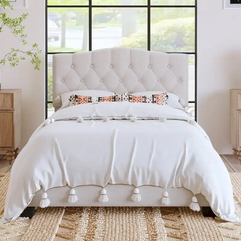 Base de cama tapizada con plataforma, cabecero curvo tipo silla de montar y detalles de rombos capitoné
